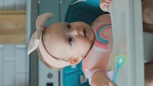 Adorable Baby Chewing Spoon in High Chair