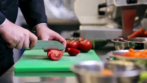 Chef cutting tomatoes on a cutting board