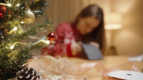 Woman Crafting Holiday Ornaments Next to Christmas Tree