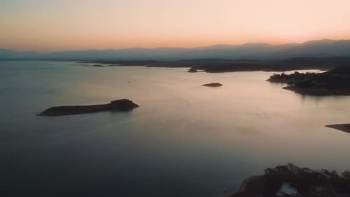 Aerial drone flying over a lake, water dam, with mountains at sunrise. Beautifull dreamy landscape