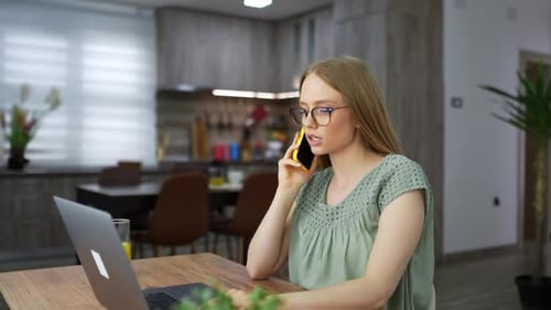 Woman Working on Laptop While Talking on Phone