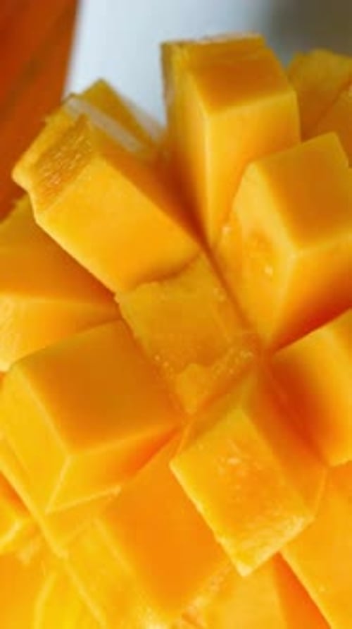 Woman eating juicy mango slice. Mango cube slices, mango fruit.