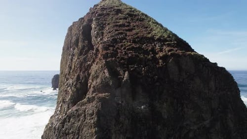 Waves in the distance pass huge rock formation on the Oregon Coastline