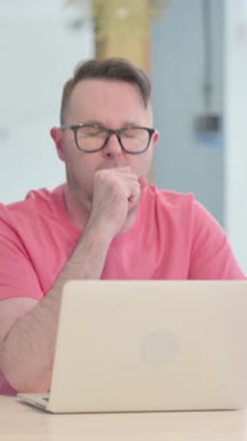 Adult Man Coughing While Using Laptop at Work