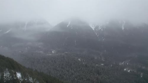 4K Drone Footage of mountains covered in fog. Winter evergreen forest.