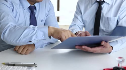 Businessmen Discussing and Signing Documents in Office