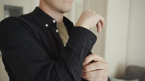 Man Rolling Up Sleeves of Black Button-Down Shirt