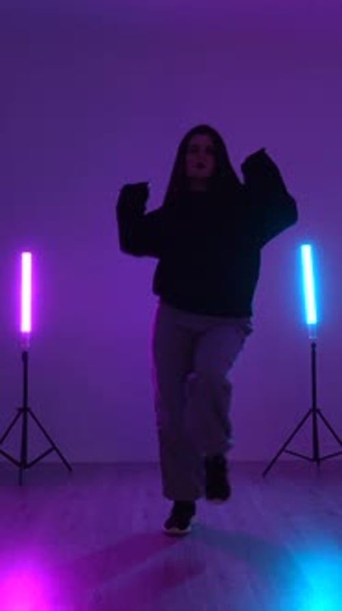 Young talented dancer performing energetic moves in studio with neon lights