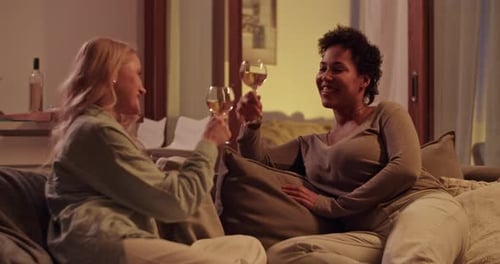 Joyeuses femmes multiethniques tintant des verres à vin dans le salon