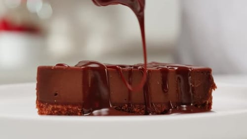 Chocolate Sauce Being Poured on Dessert Cheesecake