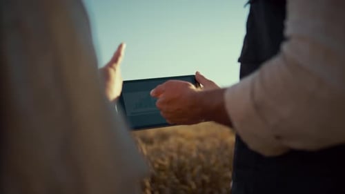 Man and child using a tablet in a field