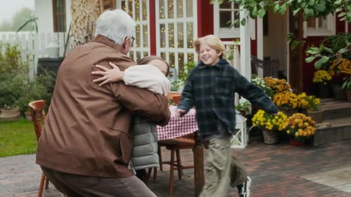 Grandfather Embracing Grandchildren in Fall Garden Setting