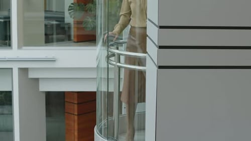 Office Colleagues Looking Down Through Panoramic Lift at Atrium Below