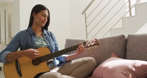 Woman Plays Acoustic Guitar on Couch at Home