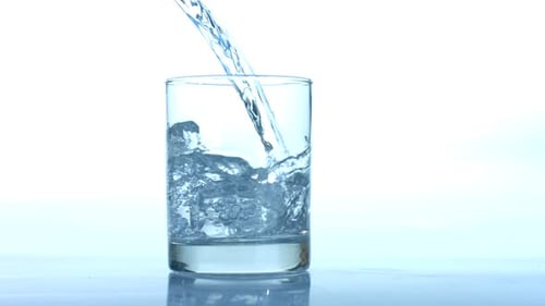 Water Being Poured Into Glass With Ice Cubes