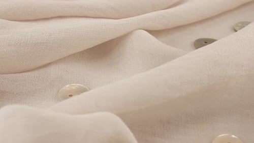 Top view of thin pink salt white color chiffon fabric and natural mother-of-pearl buttons