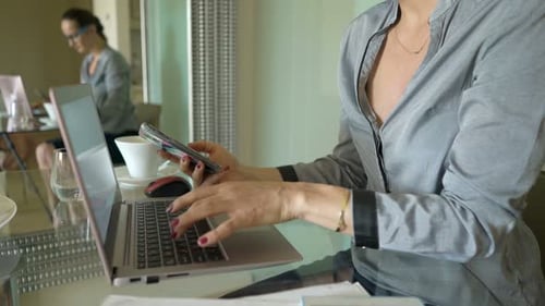 Young businesswoman working with smartphone and laptop in modern office