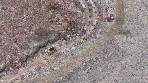 Top down aerial view of heavy and queues of garbage trucks dumping plastic and household waste at a