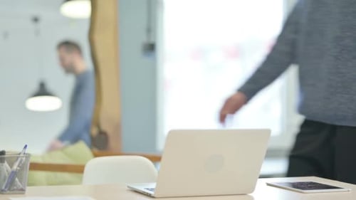 Hombre de mediana edad que regresa a la oficina y abre la computadora portátil