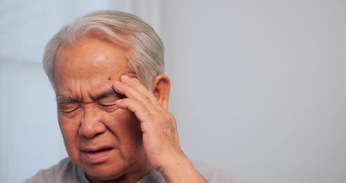 Asian old man with migraine headache. Elderly man suffering from a headache.