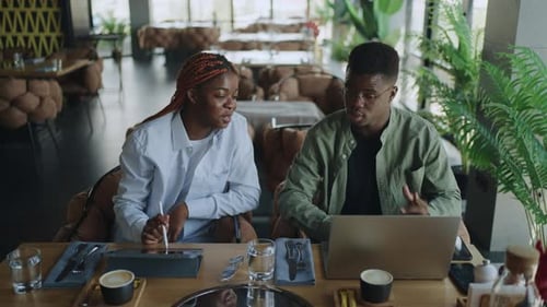 Two African American Colleagues Brainstorming Ideas for Upcoming Presentation in Local Cafe