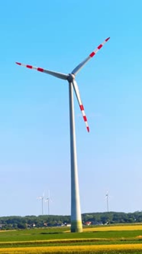 Huge wind turbine rotates in the wind. Low angle view at the wind mill producing green energy.
