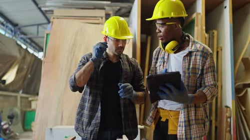 Front view of African American carpenter or woodworker or charpentier man use tablet to consult