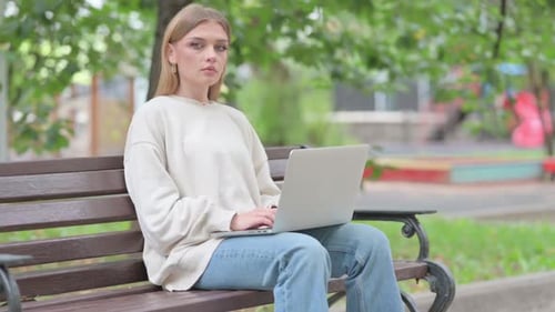 Young Woman Working on Laptop in Urban Park