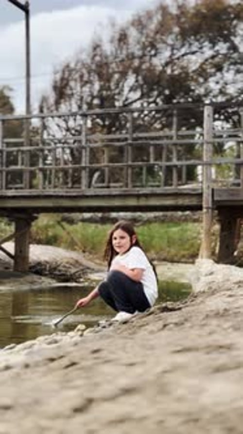 Young Girl Sitting By a Creek Near the Beach Engaging with Nature and Enjoying a Quiet Moment