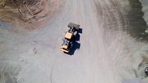 Radlader mit Schaufel, die sich zwischen Kies-, Sand- und Geröllhaufen bewegt