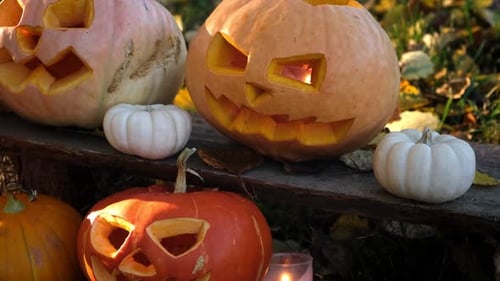 Halloween Pumpkin Head with Carved Scary Smiling Face on Wood Bench Outside JackOLantern Burning