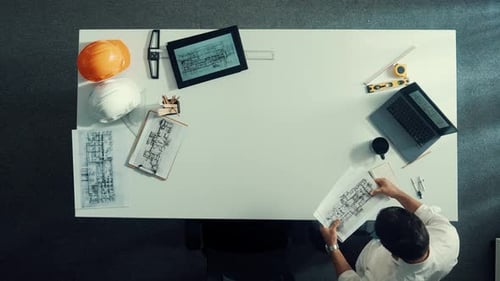 Blick von oben auf den Architekten und Ingenieur, der den Gebäudeplan auf den Tisch legt. Ernährung.