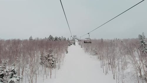 Riding on Ski Lift Above the Slopes Between Snow Covered Pinetrees POV Shot Winter Vacation Concept