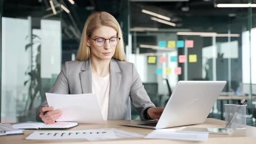 Happy businesswoman satisfied with financial results sitting at workplace in office. Smiling female