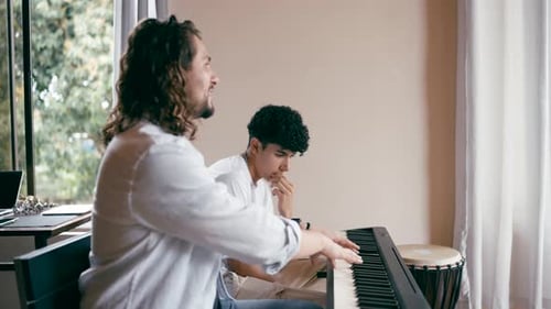 Teen Learns Piano from Young Adult in Home