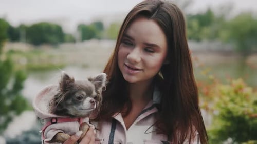 Young Woman Holding Chihuahua Dog in the Park