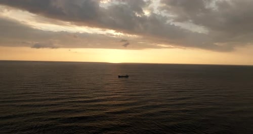 Flying over navigating cargo ship with sunset in background