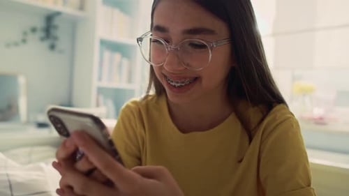 Teen Girl Using Smartphone Indoors in Bright Bedroom