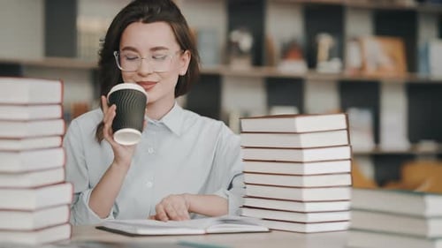 Young female student drinking coffee while studying in a library