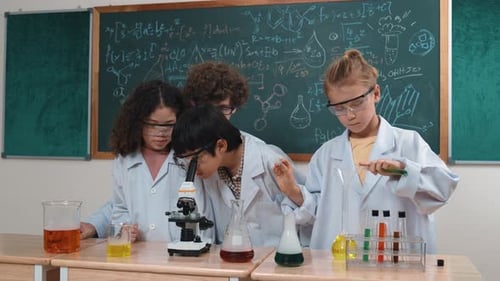 Cute children looking under microscope while student prepare solution. Pedagogy.
