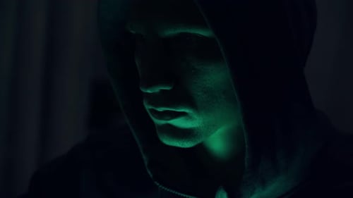 Porträt eines einschüchternden männlichen Hackers mit Kapuze. Nervöser Blick. Nahaufnahme.