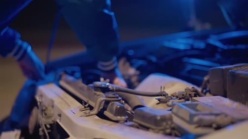 Mechanic Hands Working on Car Engine at Night