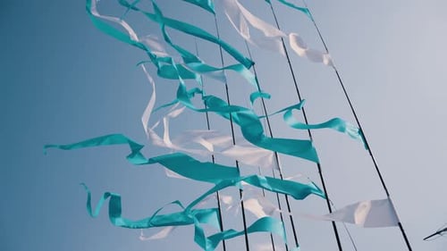 Flowing Teal and White Flags Against a Blue Sky