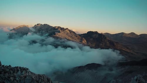 Majestic Mountain Peaks Rising Above A Thick Layer Of Clouds