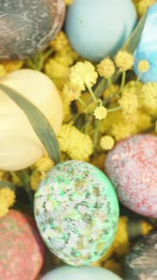 Vertical video. Easter eggs in a basket on the grass, top view. The camera rotates and rises higher.