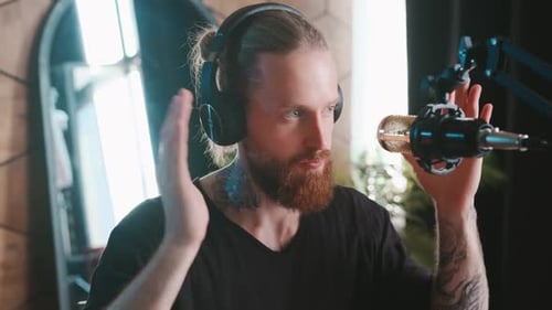 Young Charismatic Caucasian Man Gestures Recording Audio Podcast Sits in Studio