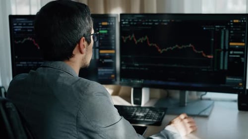 Man Analyzing Stock Market Data on Computer Screens