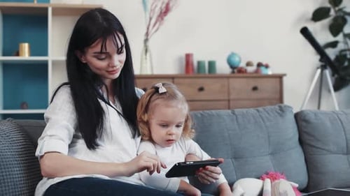 Woman and Child Play Game on Tablet