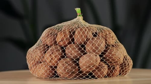 Whole Walnut in a Mesh Bag Rotating on Wooden Desk Closeup Walnuts in a Shell Healthy Snacks Product