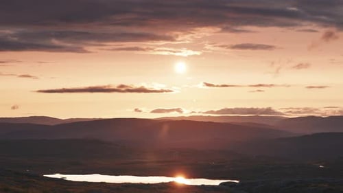 Midnight sun passes on the horizon casting warm light over the landscape. Timelapse video.